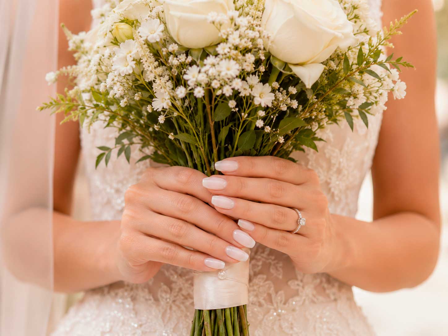 Unhas claras para noivas com esmaltação branco leitoso e buquê delicado